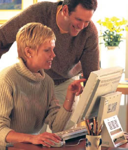 image: woman pointing at computer screen with man looking over her shoulder and smiling