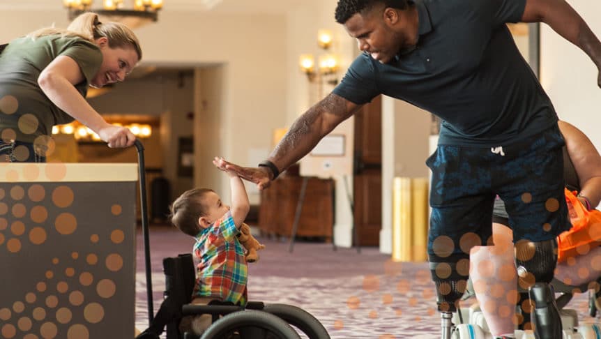 Man and child, both living with double lower limb loss, giving high five